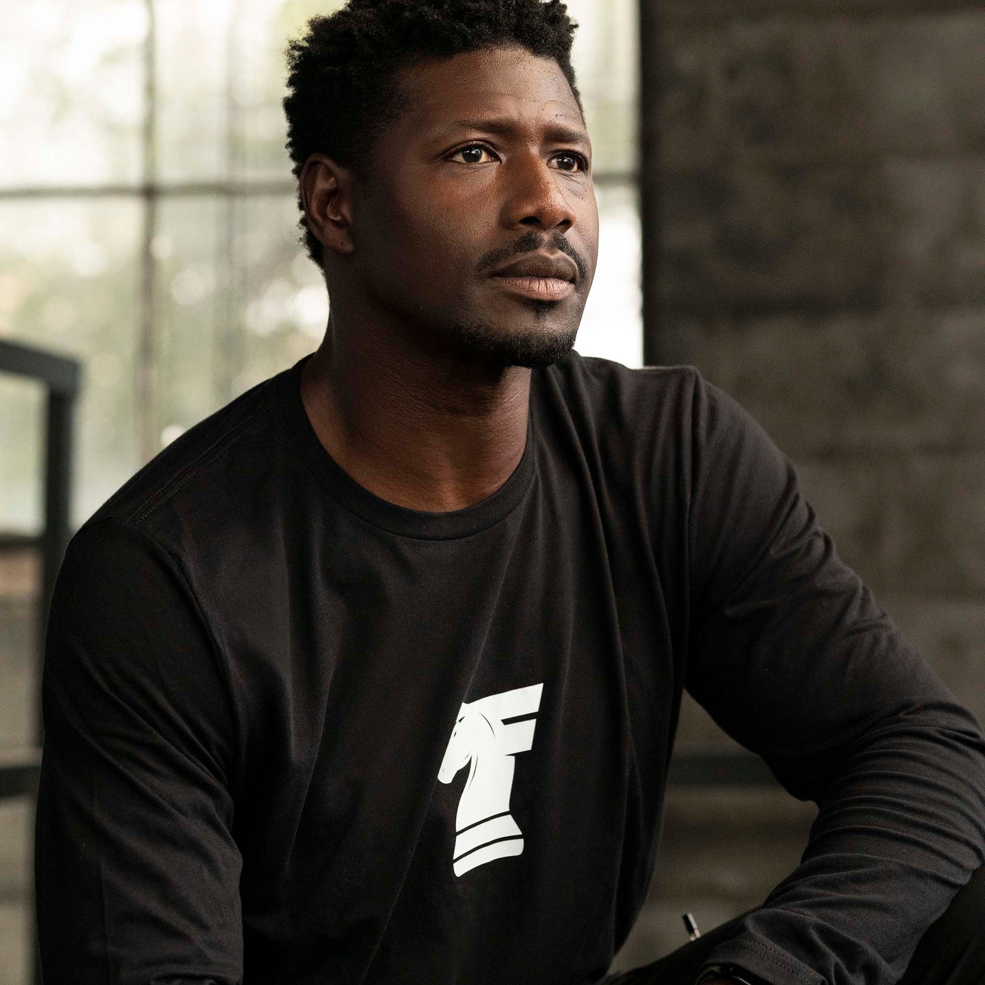 Man wearing Workhorse's Classic Long Tee in black, sitting indoors.